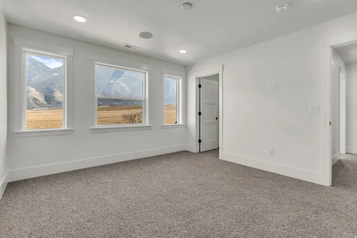 White walls, recessed lighting, gray carpet, white trim, and multiple windows
