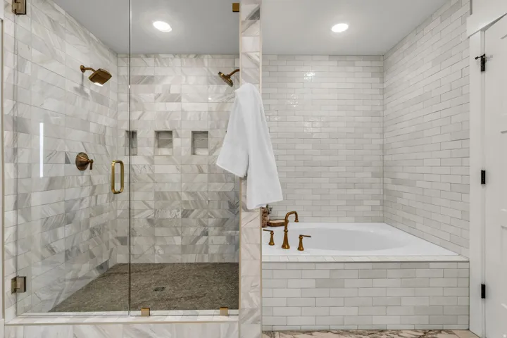 Glass-enclosed shower with multiple shower heads and integrated wall niches