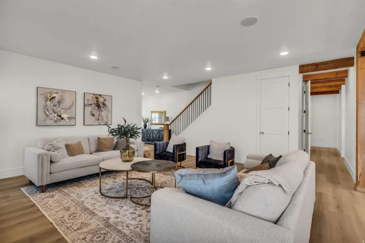 Recessed lighting, wood-finish flooring, white walls, and a staircase with dark wood handrail and black balusters