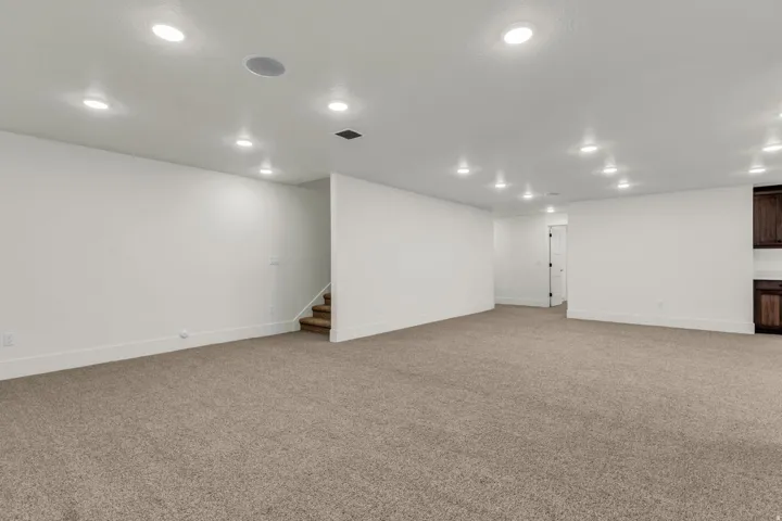 Expansive carpeted area with recessed lighting, integrated ceiling speakers, and light-toned walls