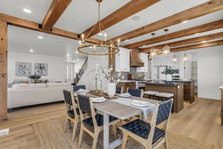 Exposed wood ceiling beams, wood-finish flooring, and a brass chandelier provide architectural character