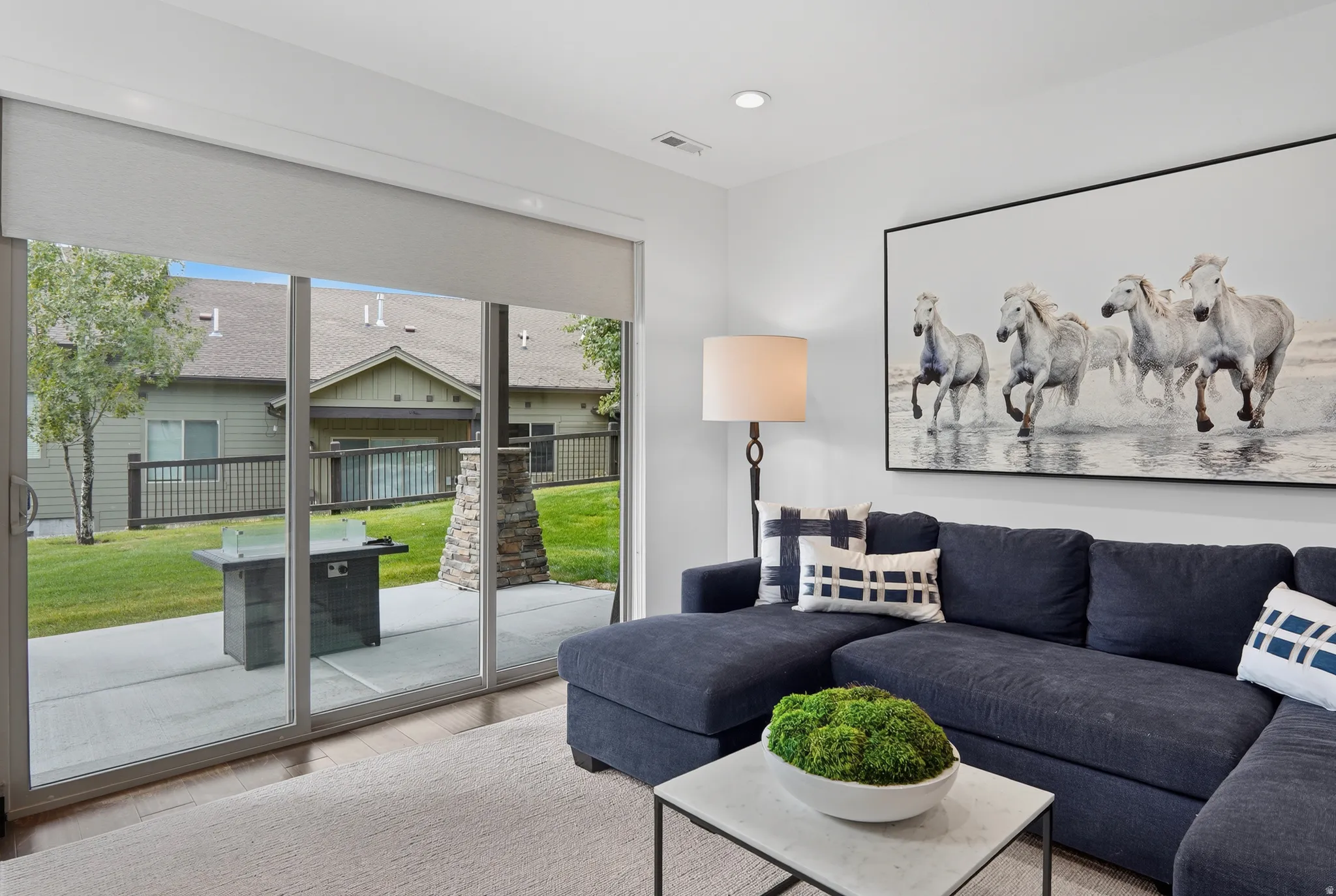 Sliding glass door with integrated shade, wood-finish flooring, and recessed lighting