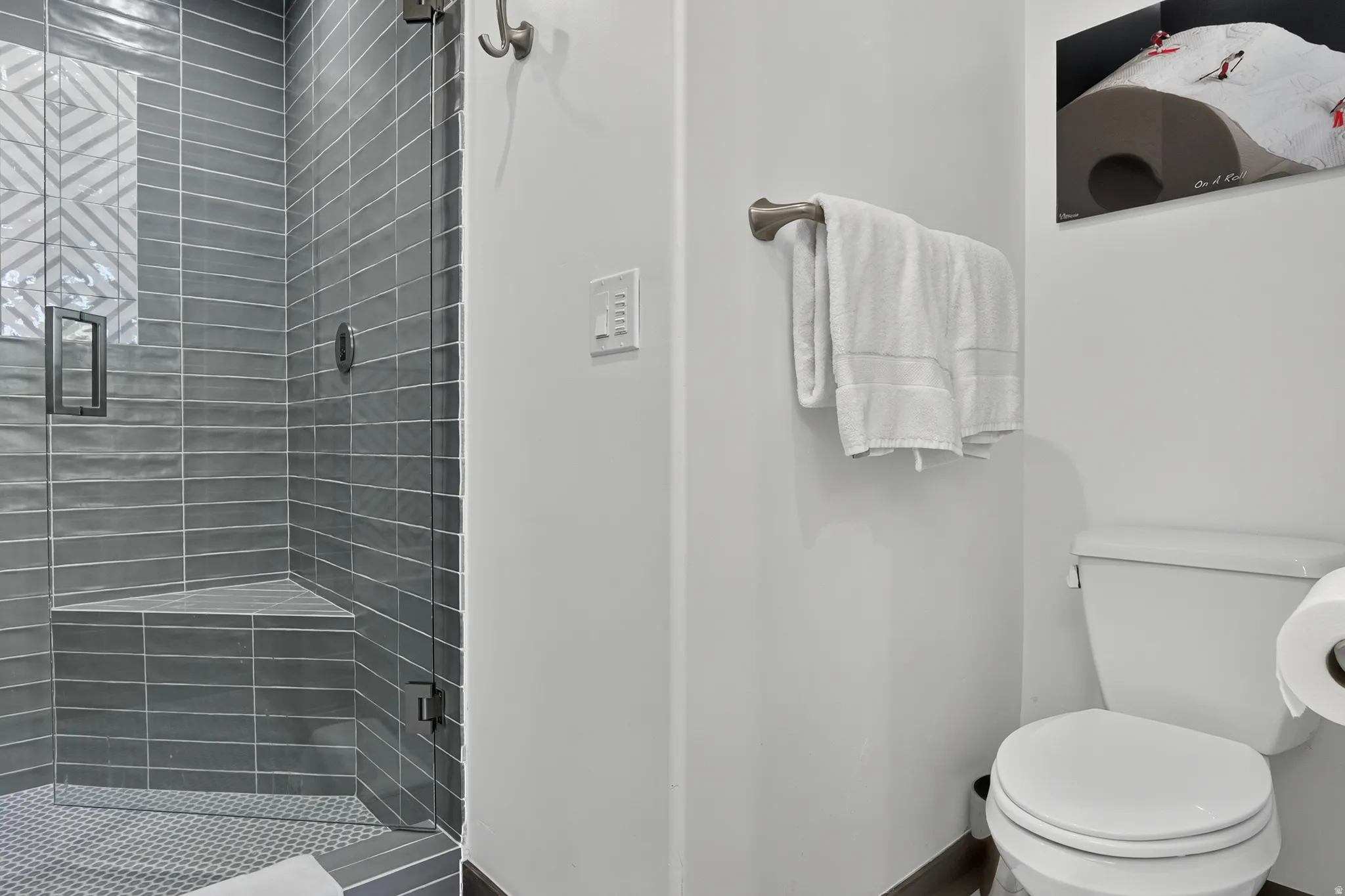 Shower with a glass enclosure, gray subway tile, and a built-in bench