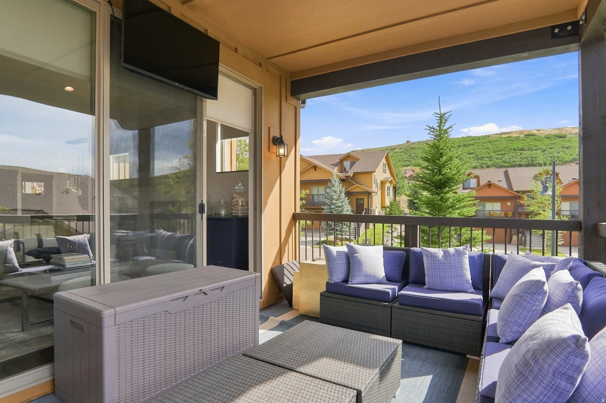 Covered outdoor living area featuring a wood-finish ceiling, sliding glass door access, exterior wall sconces, and a dark wood railing