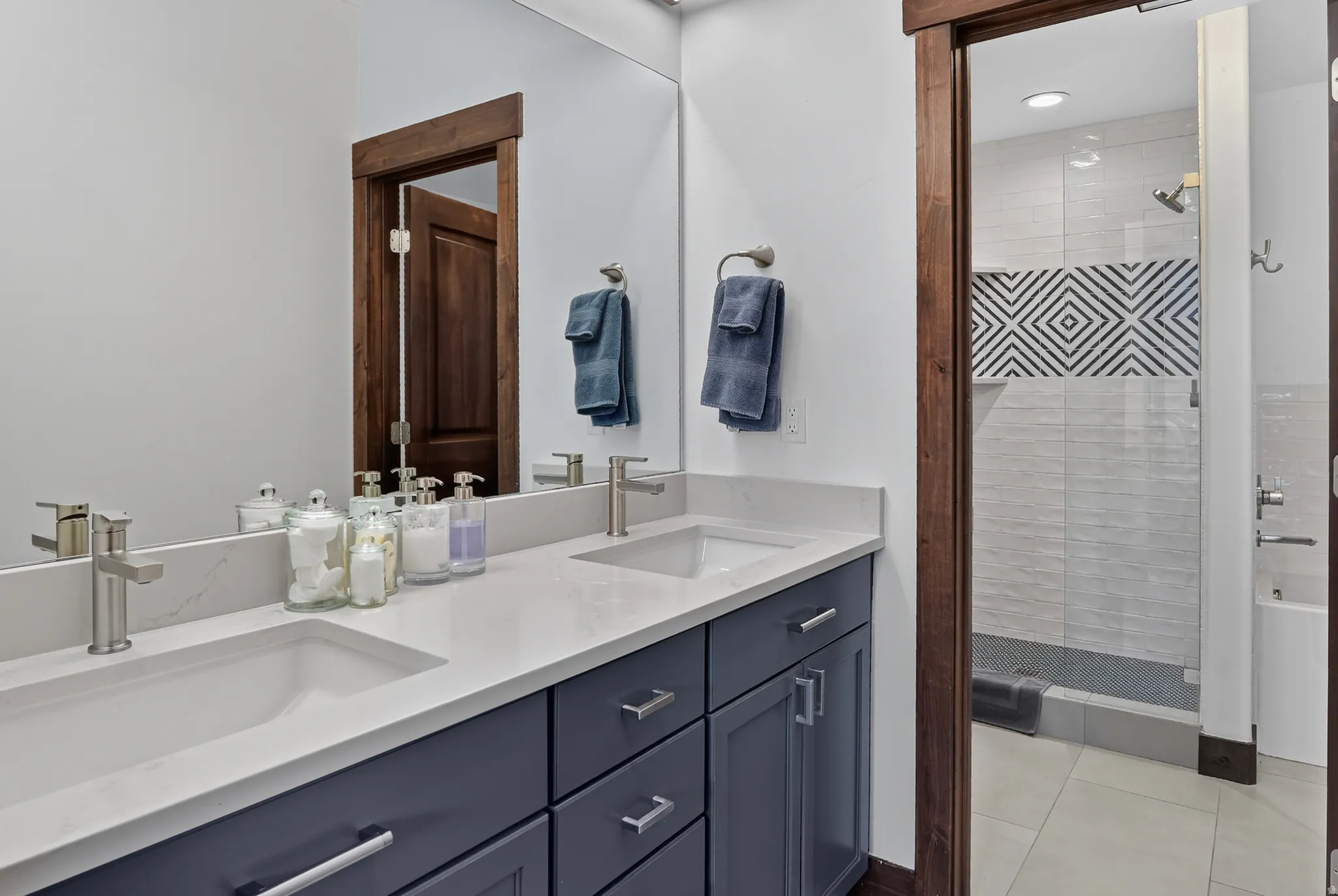 Dual undermount sinks with brushed nickel faucets, quartz countertop, and dark wood-finish cabinetry