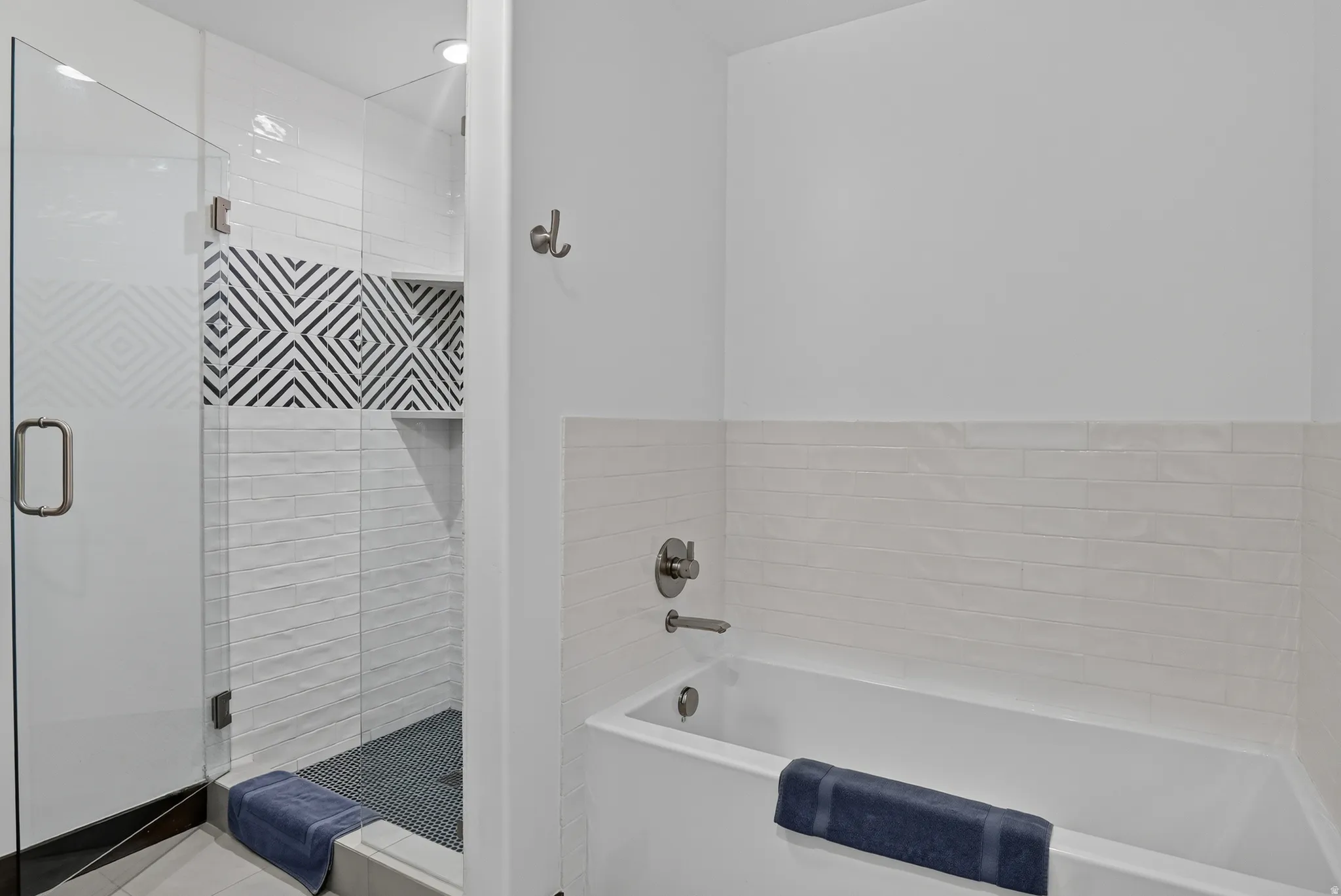 Glass-enclosed shower with a patterned accent tile, white subway tile surround, and a built-in shower niche