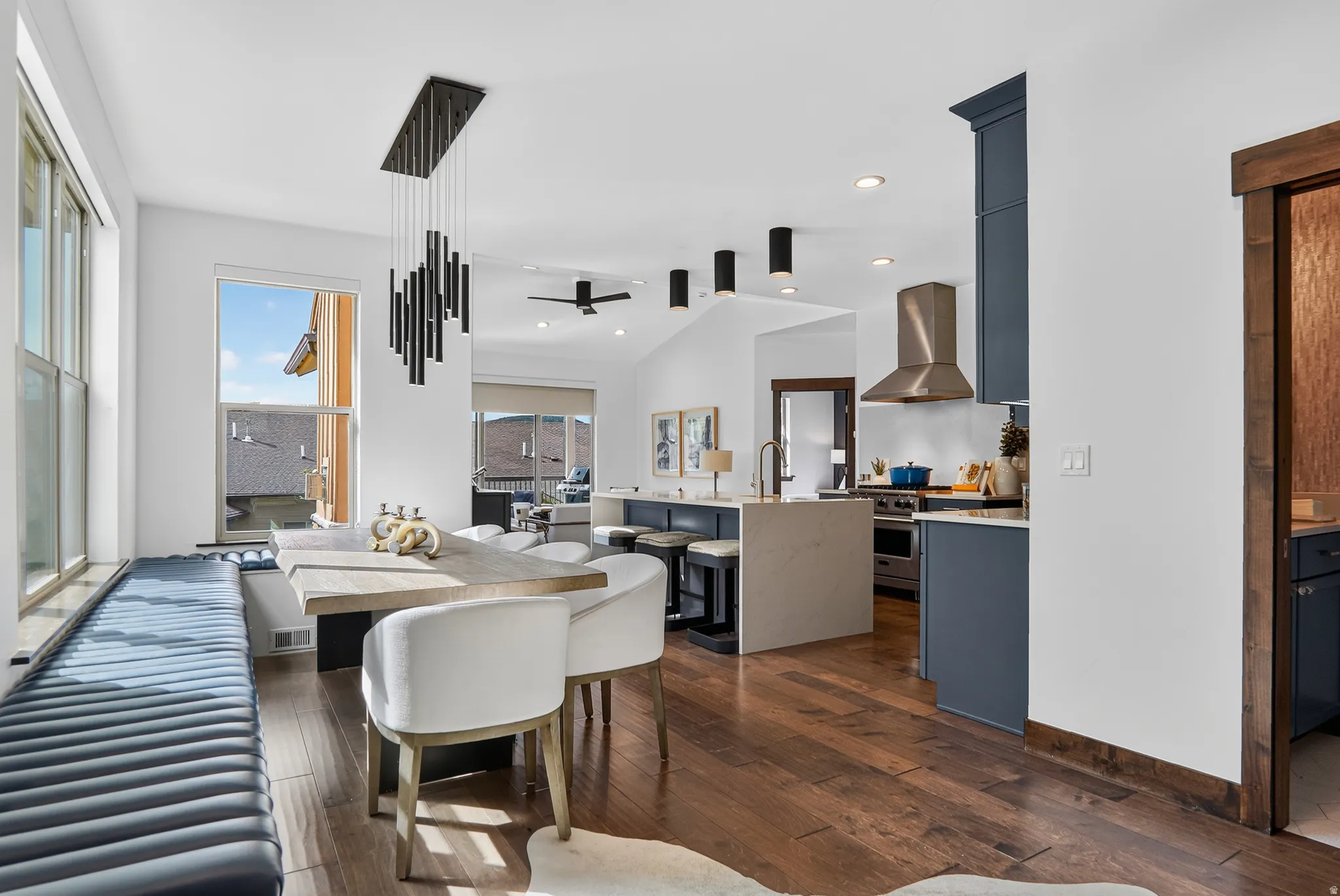 Hardwood flooring, custom window bench, modern linear chandelier, recessed lighting, and a stainless steel range hood