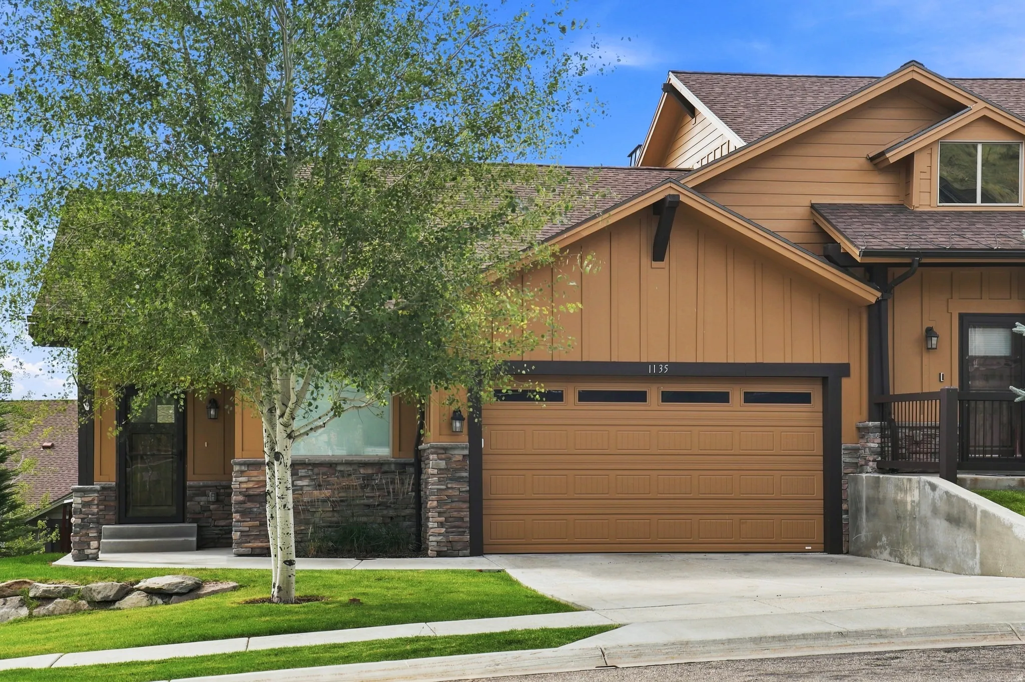 Craftsman-style facade with stone accents, horizontal siding, attached garage, and pitched rooflines