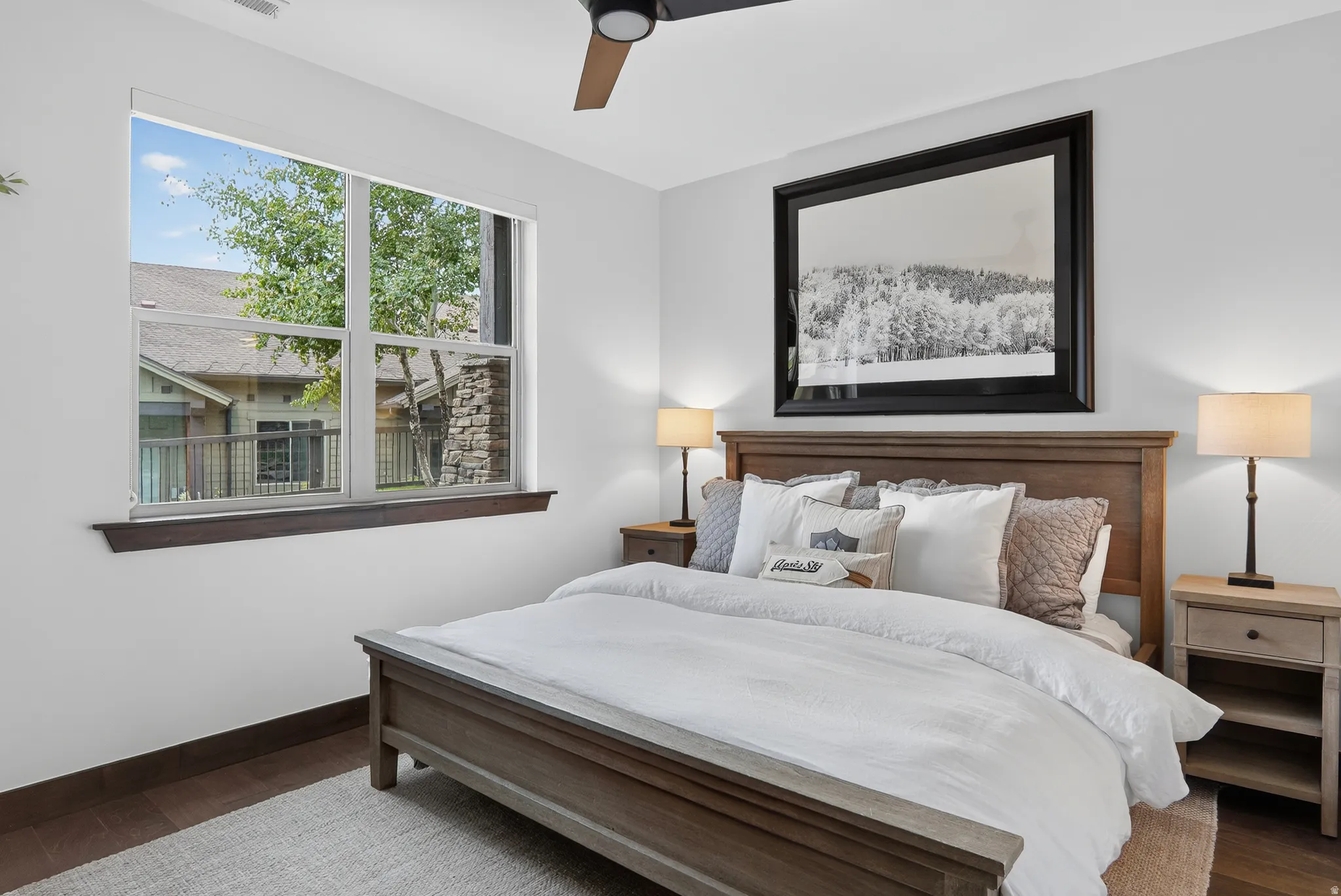 Wood-finish flooring, white walls, and a large window with dark wood trim