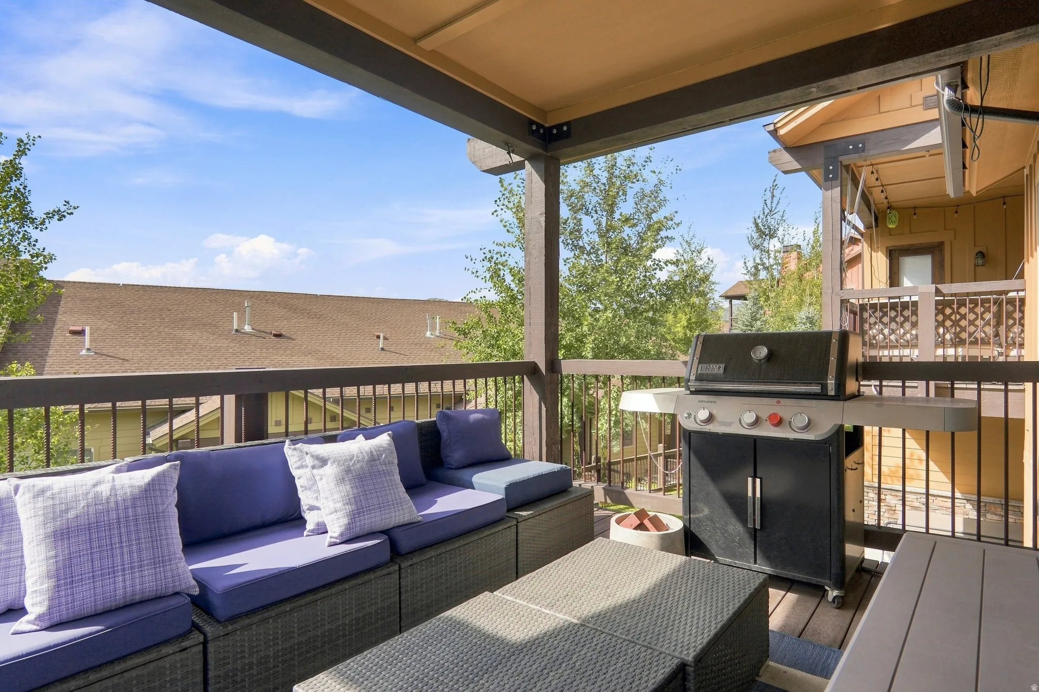 Covered outdoor deck with wood-finish flooring, dark wood railing, and integrated overhead lighting