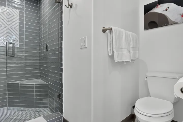 Shower with a glass enclosure, gray subway tile, and a built-in bench