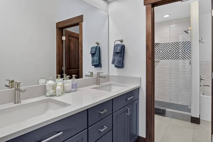 Dual undermount sinks with brushed nickel faucets, quartz countertop, and dark wood-finish cabinetry