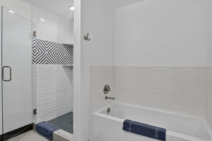 Glass-enclosed shower with a patterned accent tile, white subway tile surround, and a built-in shower niche