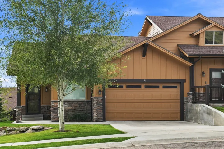 Craftsman-style facade with stone accents, horizontal siding, attached garage, and pitched rooflines