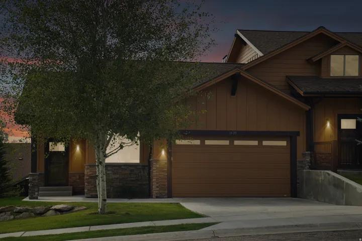 Brown siding exterior with stone accents, a two-car garage, and a covered entry