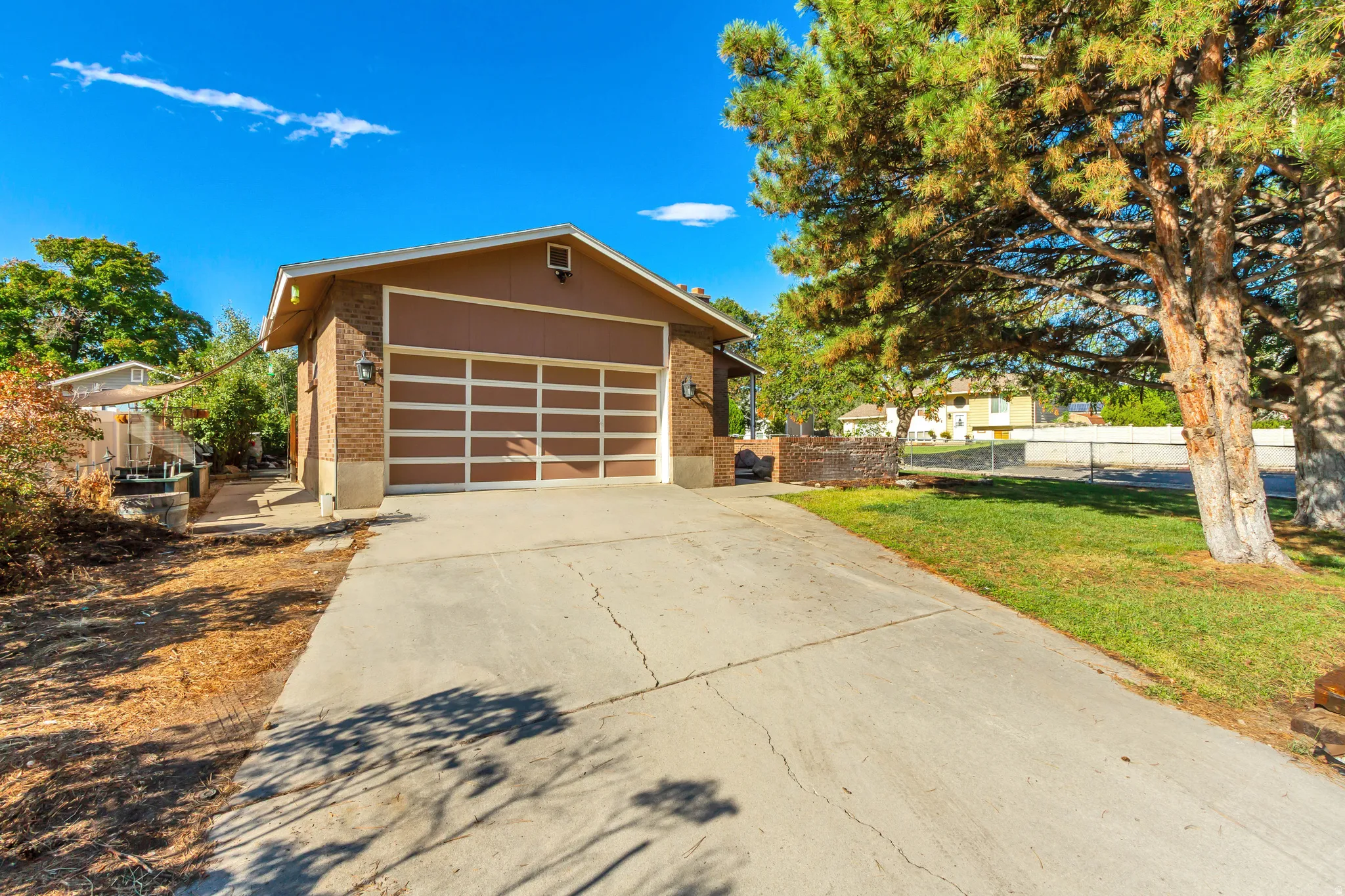 Concrete driveway leading to a brick-clad garage with a paneled door