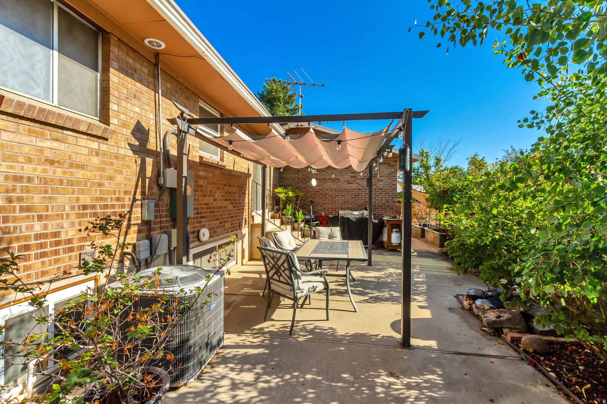 Brick exterior with a covered patio area and mature landscaping