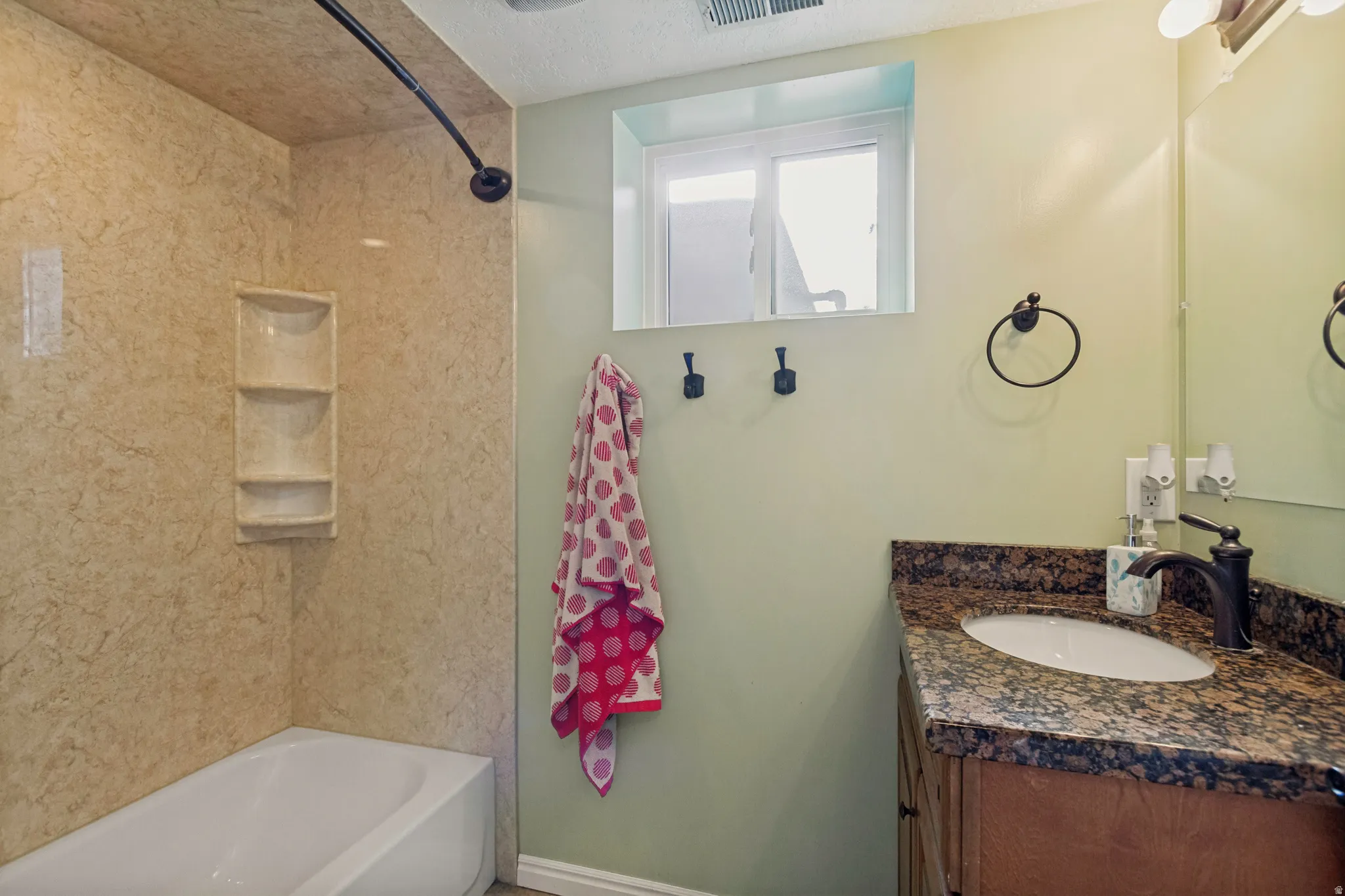 Built-in bathtub with shower, integrated shelving, and a curved shower rod