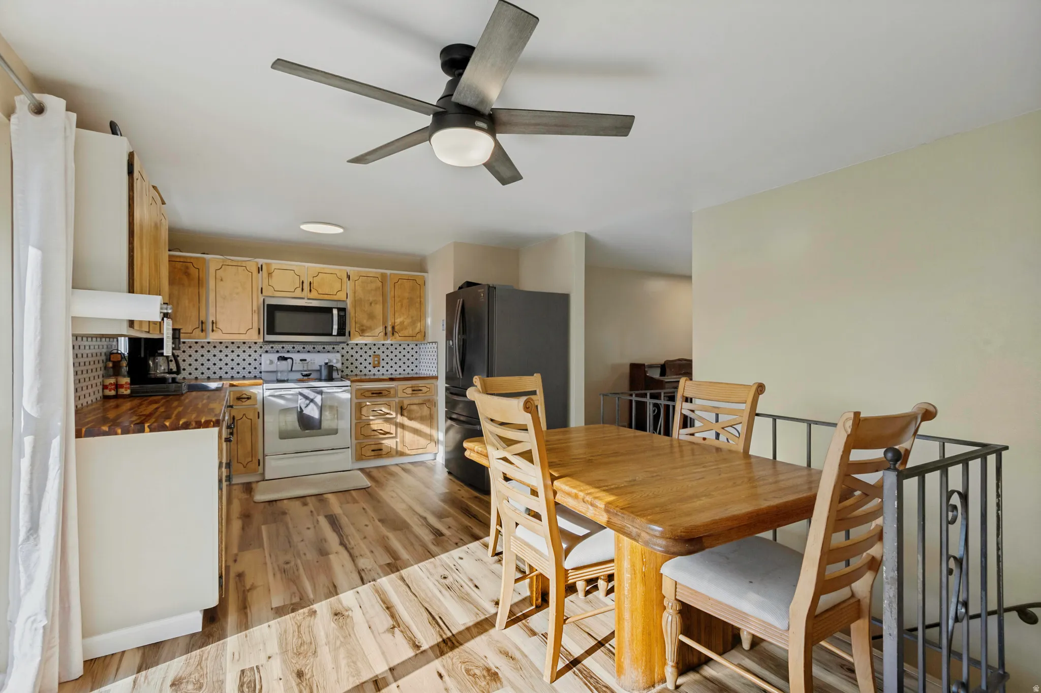 Kitchen featuring wood-finish flooring, wood cabinetry, stainless steel appliances, and a tiled backsplash