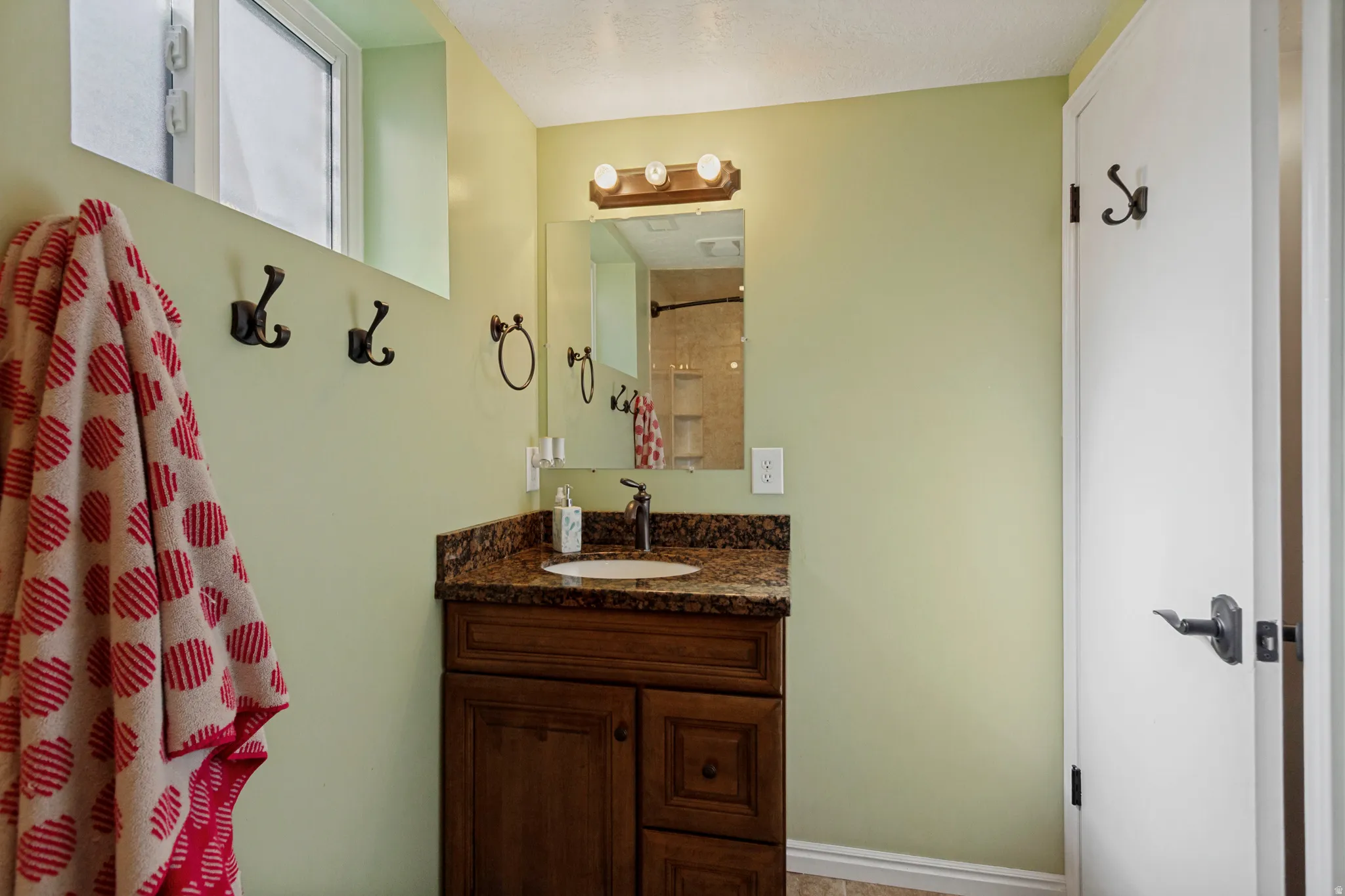 Wood-finish vanity with a built-in sink, stone-finish countertop, and wall-mounted lighting