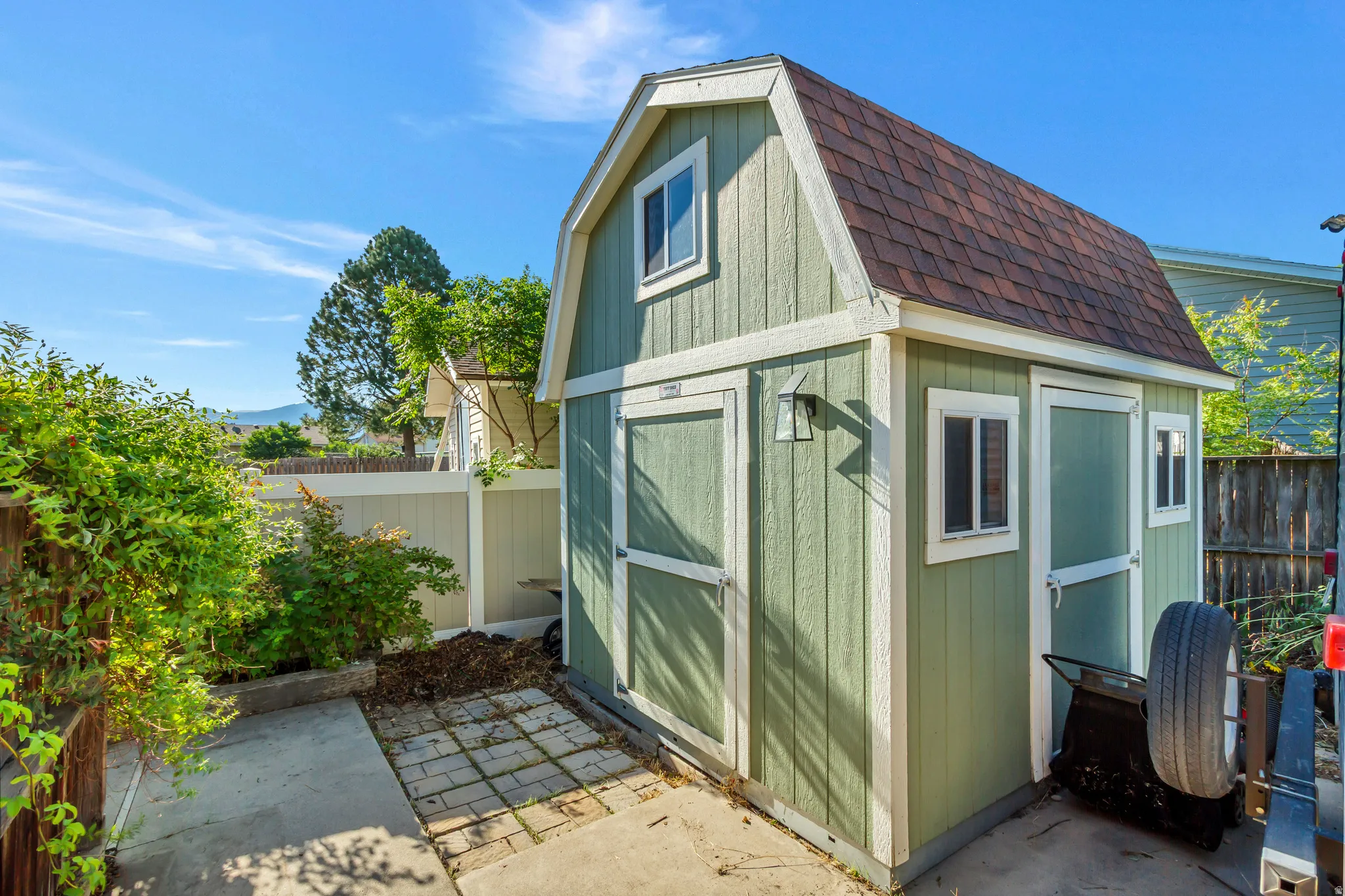 Gable-roof storage shed with green siding and white trim