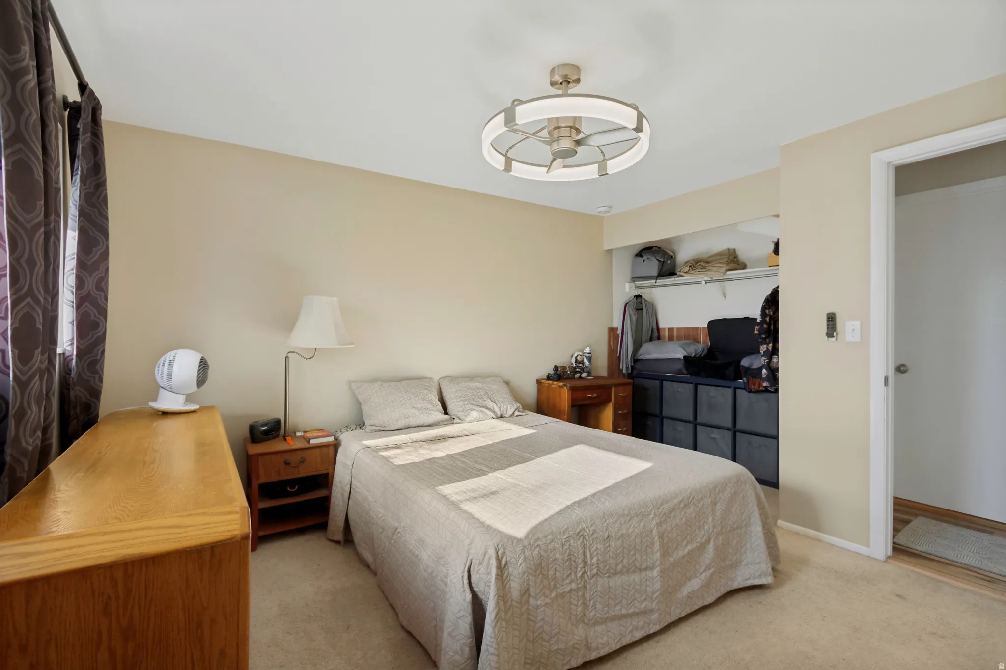 Wall-to-wall carpeting with neutral wall tones, featuring a ceiling fan with integrated lighting