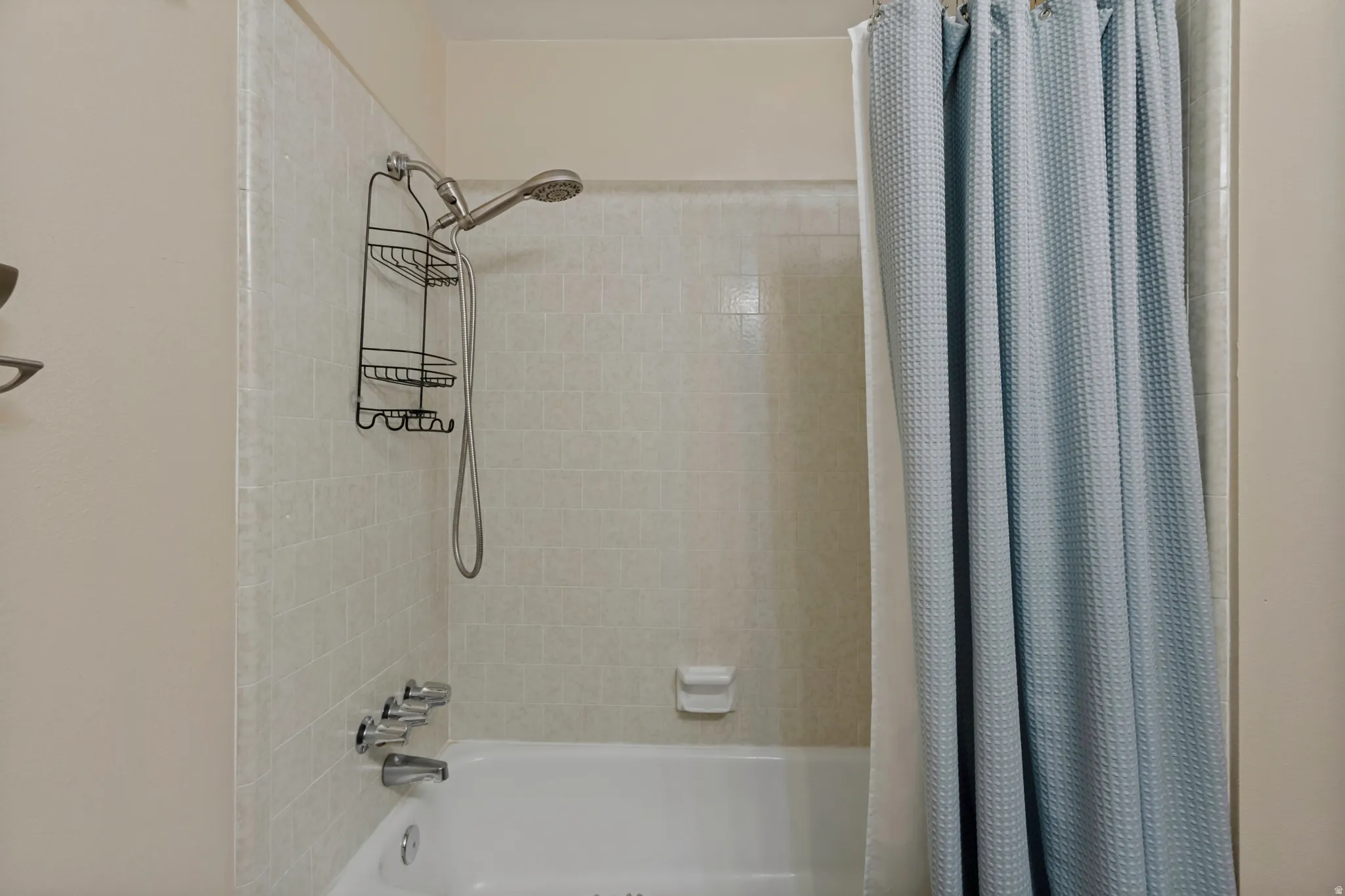 White bathtub with a tiled shower surround and chrome fixtures