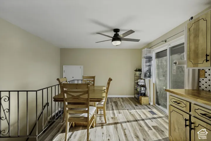 Wood-finish flooring, ceiling fan with integrated lighting, sliding glass door, and a built-in kitchen cabinet