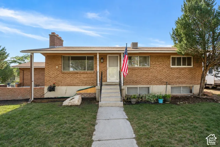 Brick exterior with multiple windows, covered front entrance, and mature landscaping
