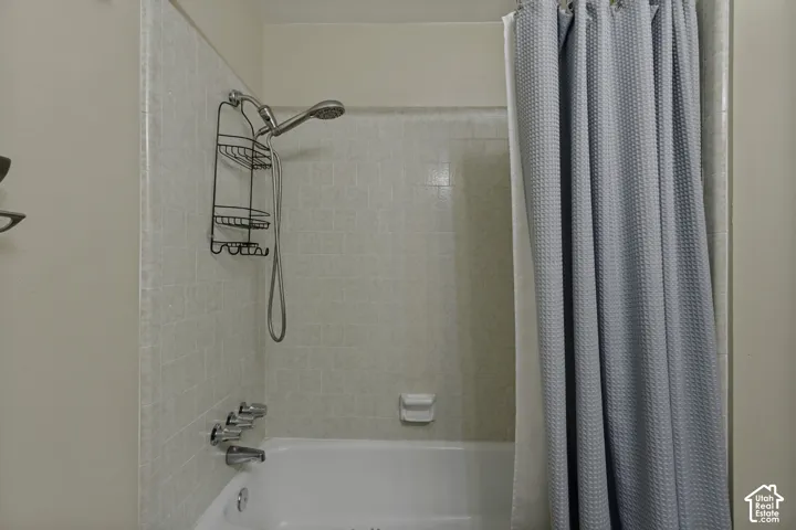 White bathtub with a tiled shower surround and chrome fixtures