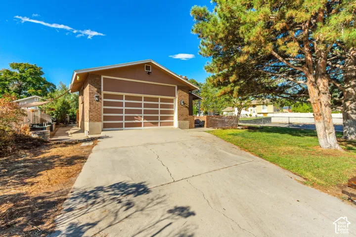 Concrete driveway leading to a brick-clad garage with a paneled door