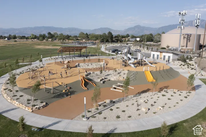 Expansive outdoor recreation area with diverse play structures, paved walking paths, a covered pavilion, and surrounding landscaping