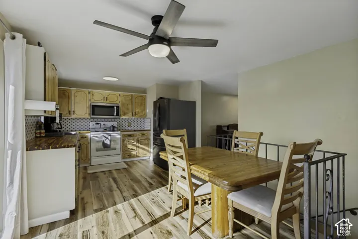 Kitchen featuring wood-finish flooring, wood cabinetry, stainless steel appliances, and a tiled backsplash