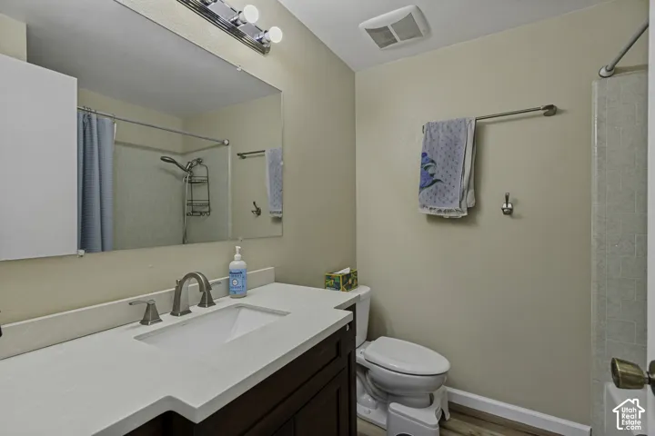 Vanity with integrated sink, brushed nickel faucet, large wall-mounted mirror, and wood-finish flooring