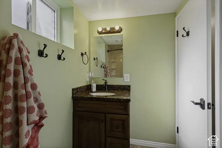 Wood-finish vanity with a built-in sink, stone-finish countertop, and wall-mounted lighting