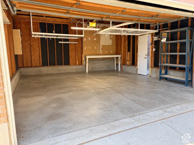 Spacious garage with concrete flooring, built-in shelving, a workbench, and overhead storage racks
