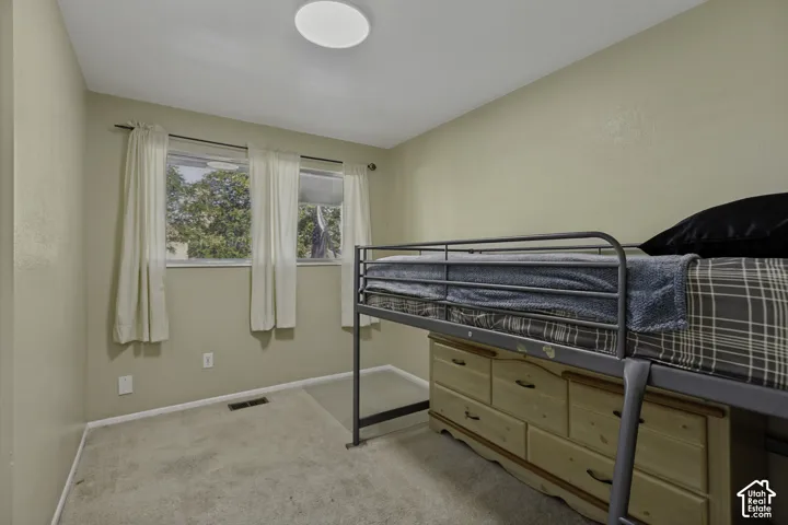 Wall-to-wall carpeting and three windows with white curtains