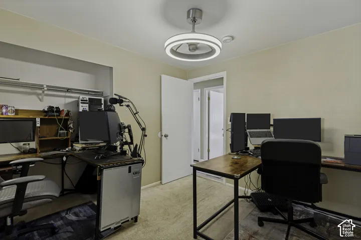 Neutral-toned wall finish, recessed shelving with hanging rods, wood-finish desktop, and a modern ceiling fan with integrated lighting