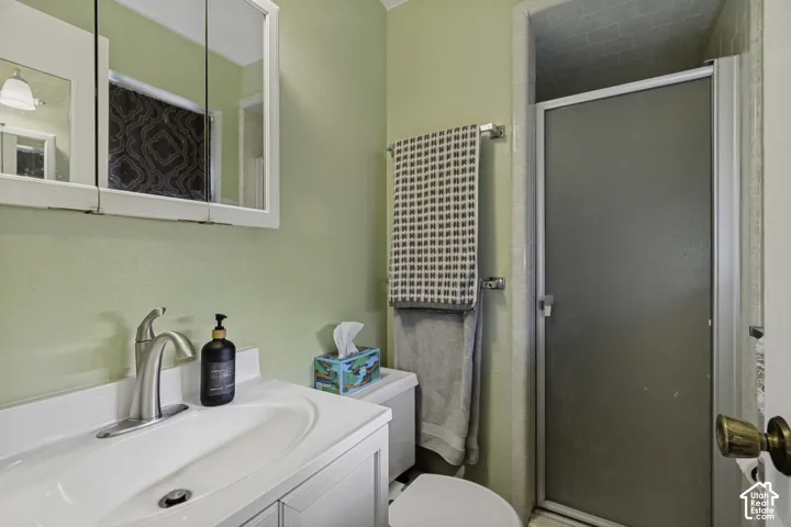 Bathroom featuring a white vanity with integrated sink, brushed nickel faucet, wall-mounted medicine cabinet, and a shower with a frosted glass door