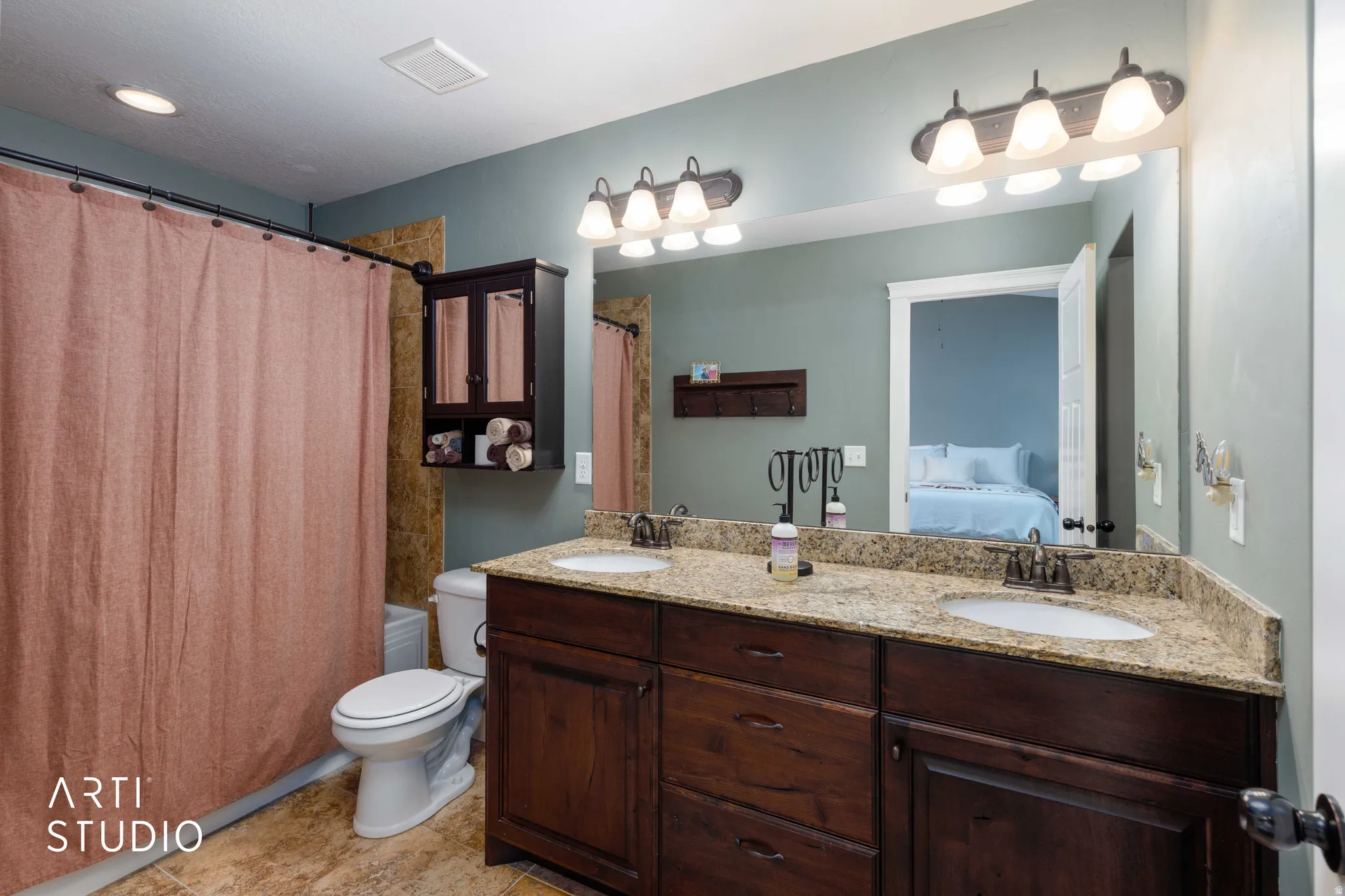 Double vanity with granite-style countertop, recessed lighting, wall-mounted light fixtures, and built-in storage cabinet