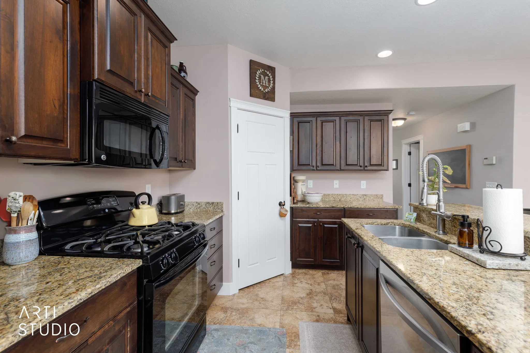 Kitchen featuring dark wood-finish cabinetry, light-toned granite countertops, stainless steel appliances, and tile flooring