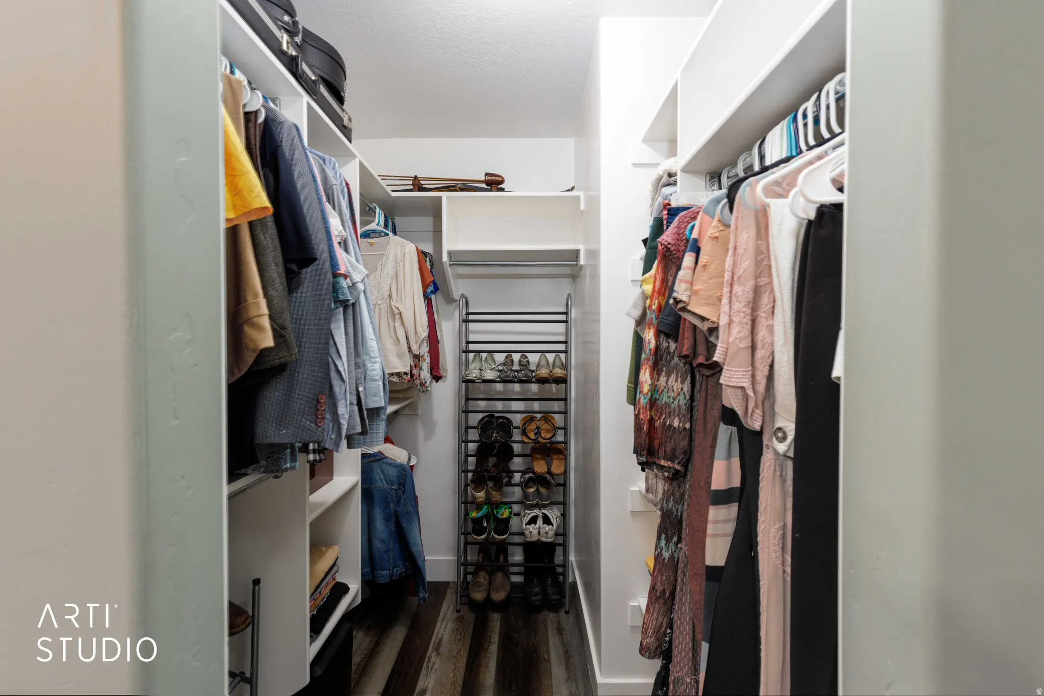 Walk-in closet featuring built-in shelving, hanging rods, and wood-finish flooring