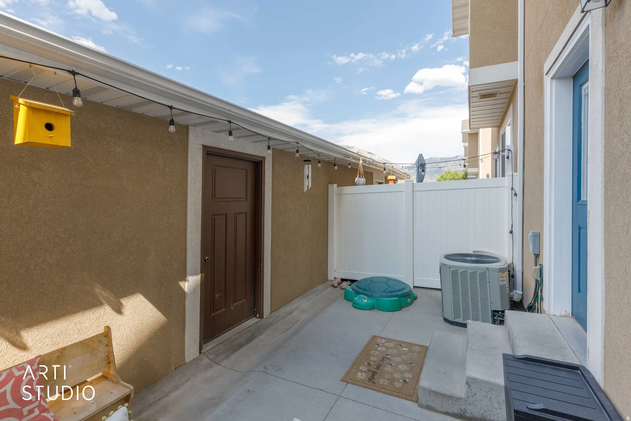 Enclosed concrete patio area featuring a privacy fence, exterior door, and an air conditioning unit