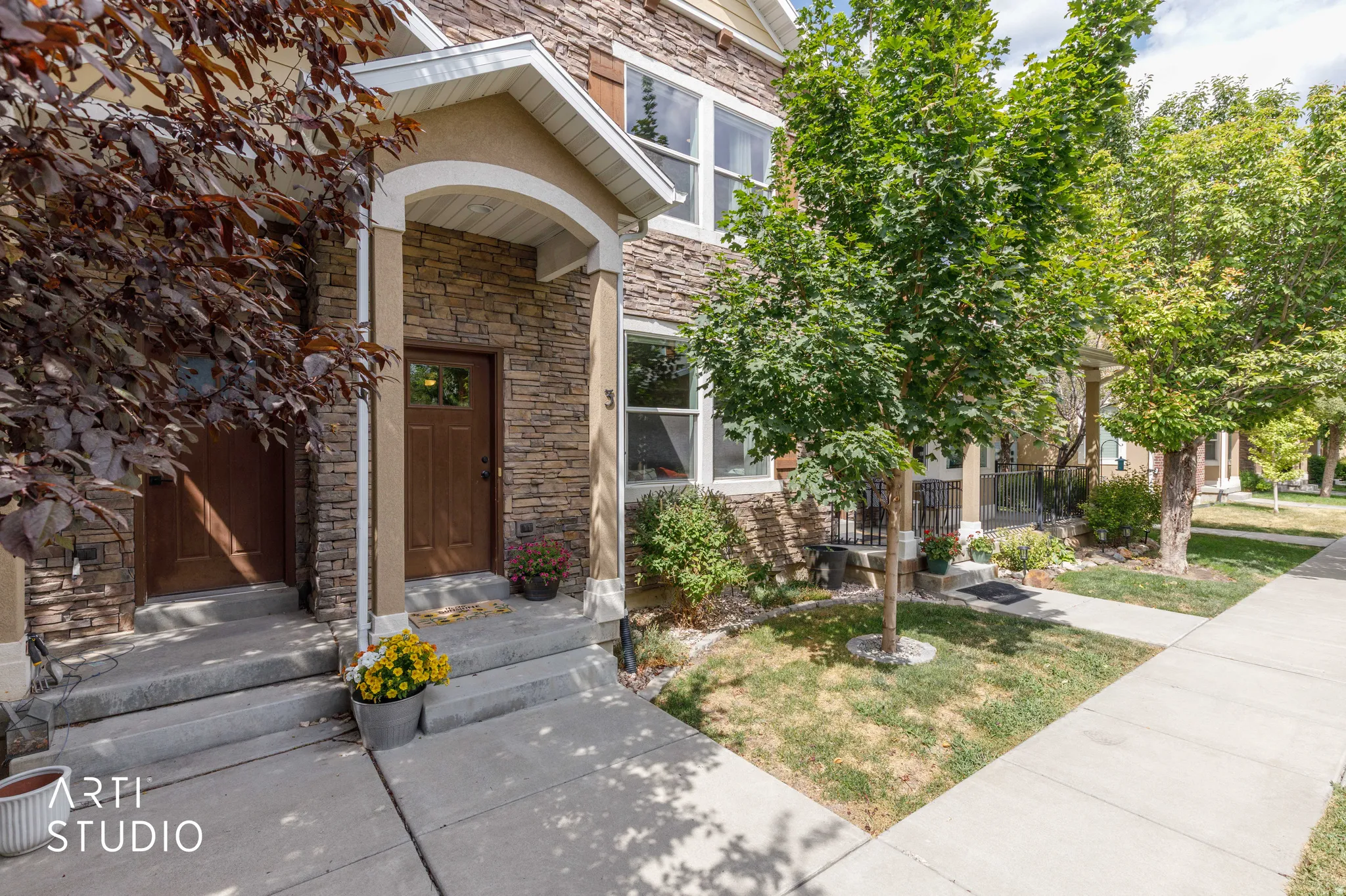 Stone facade with a covered entry, concrete steps, and a sidewalk