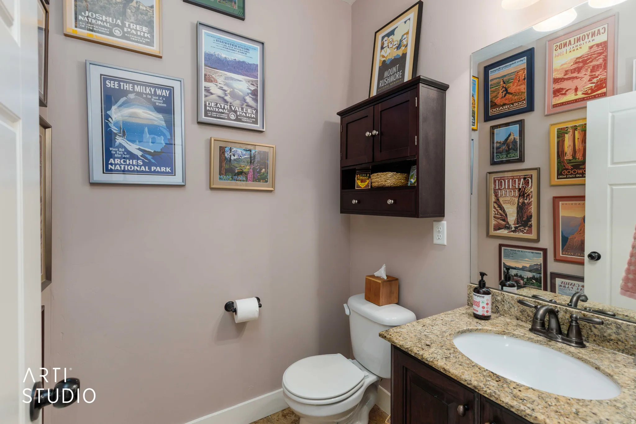 Bathroom with a built-in wood vanity, stone countertop, undermount sink, and wall-mounted storage cabinet