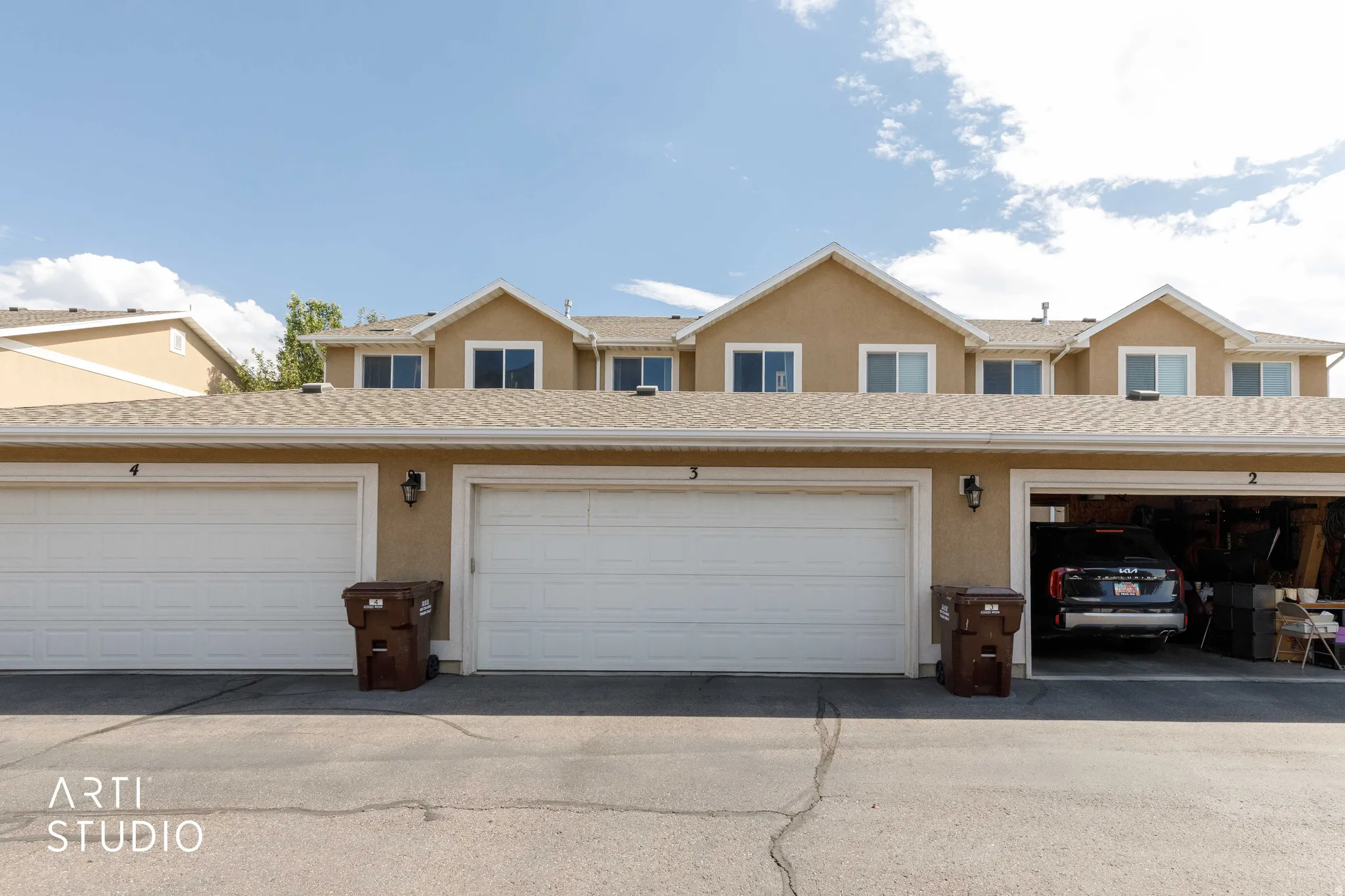 Multi-unit property with a stucco exterior, multiple attached garages, and individual lighting fixtures
