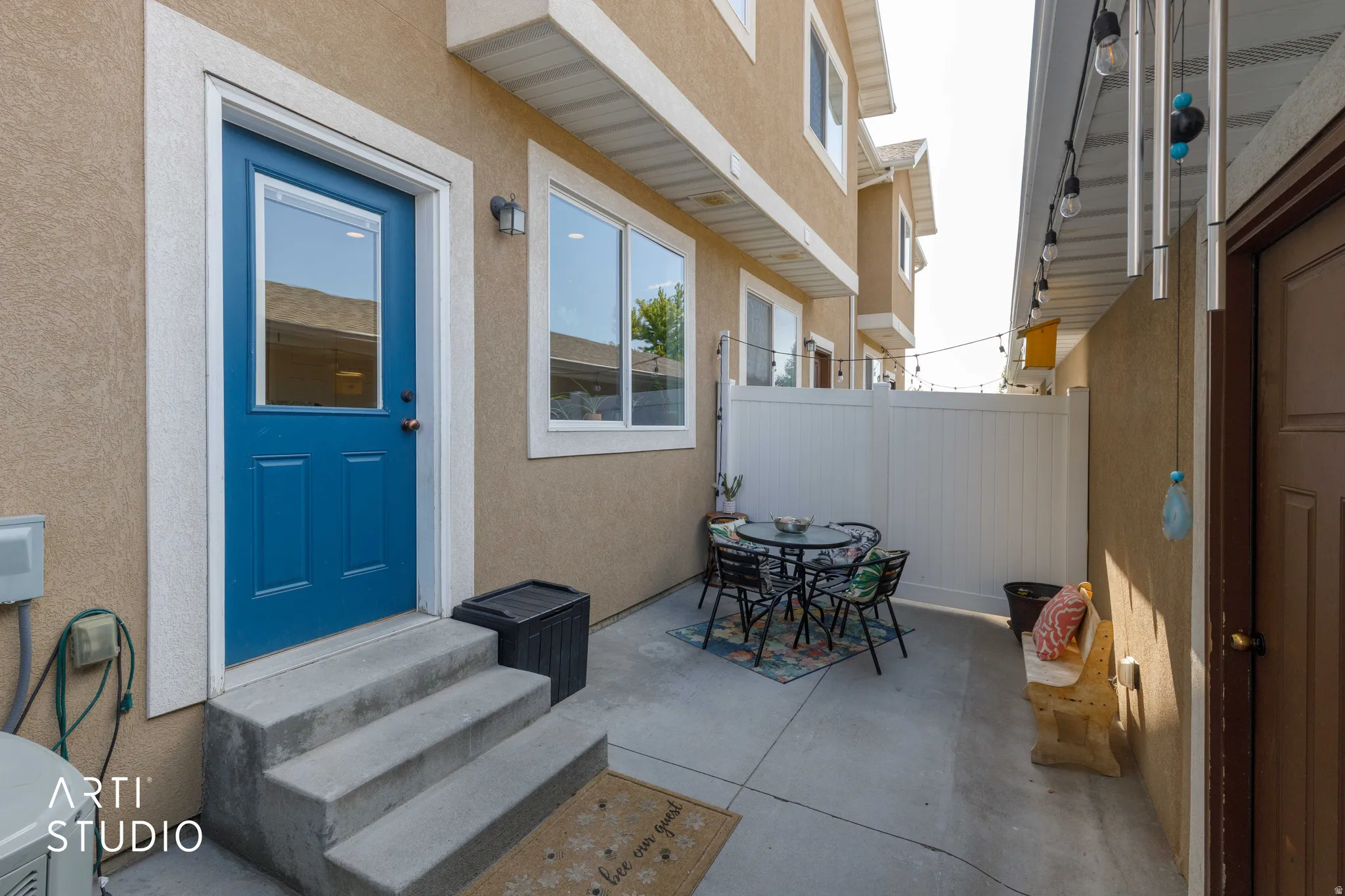 Private patio with a white vinyl privacy fence, concrete steps, and a blue entry door with an upper window panel