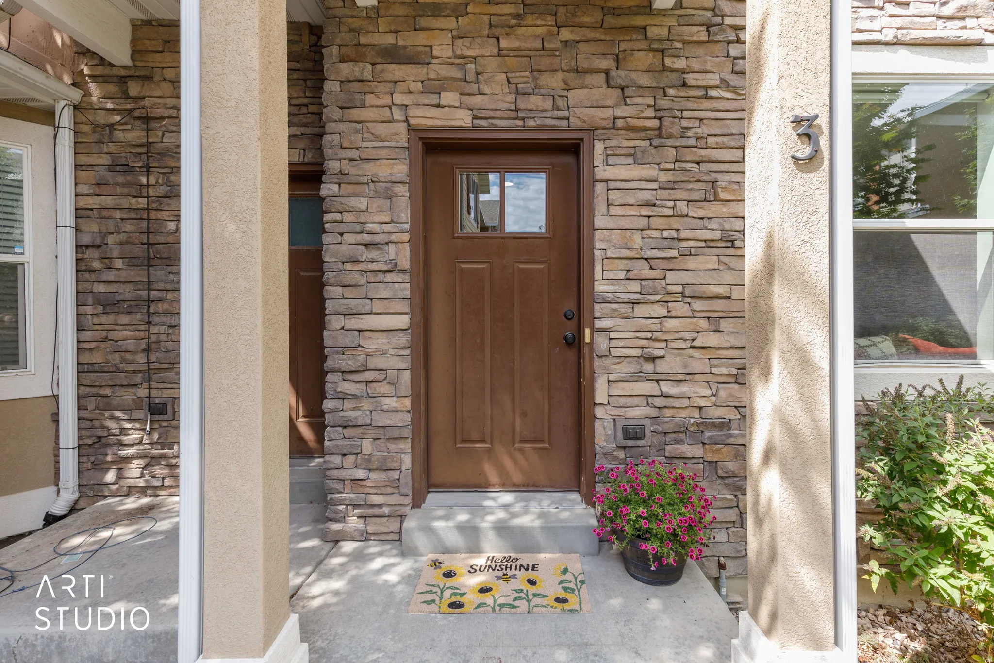 Stone veneer exterior with a brown entry door featuring divided lites
