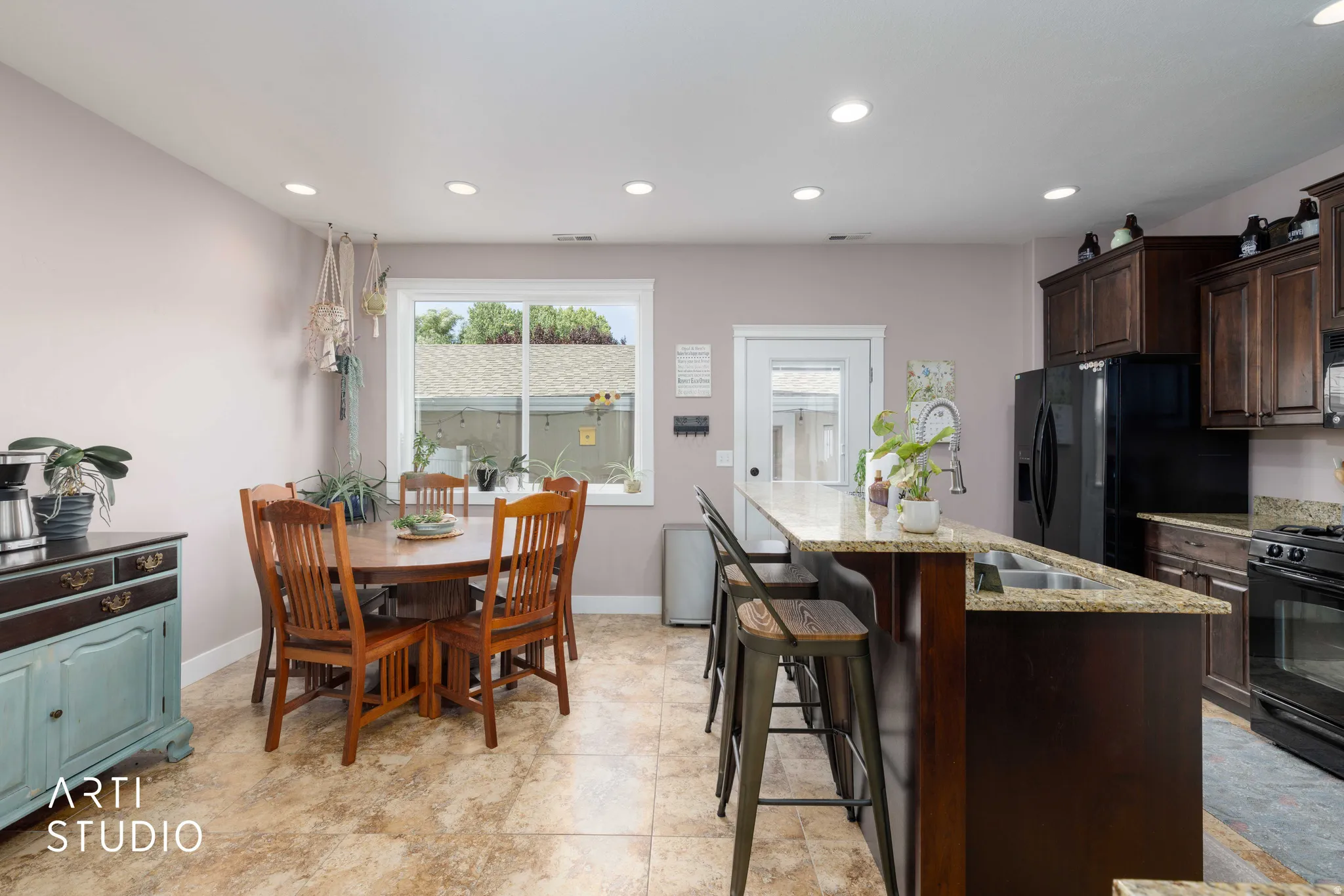 Recessed lighting, wood-finish cabinetry, granite countertops, and black appliances