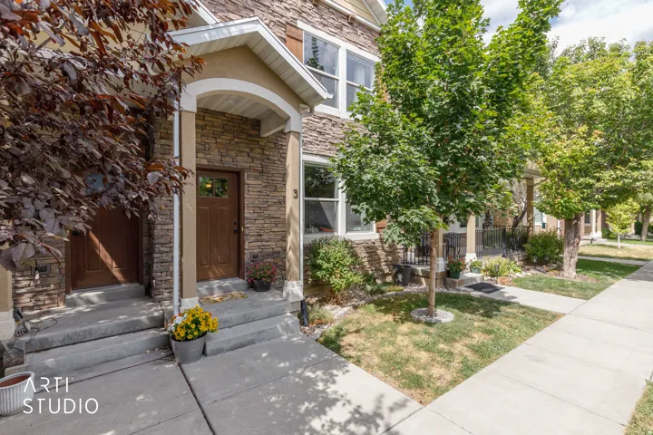 Stone facade with a covered entry, concrete steps, and a sidewalk